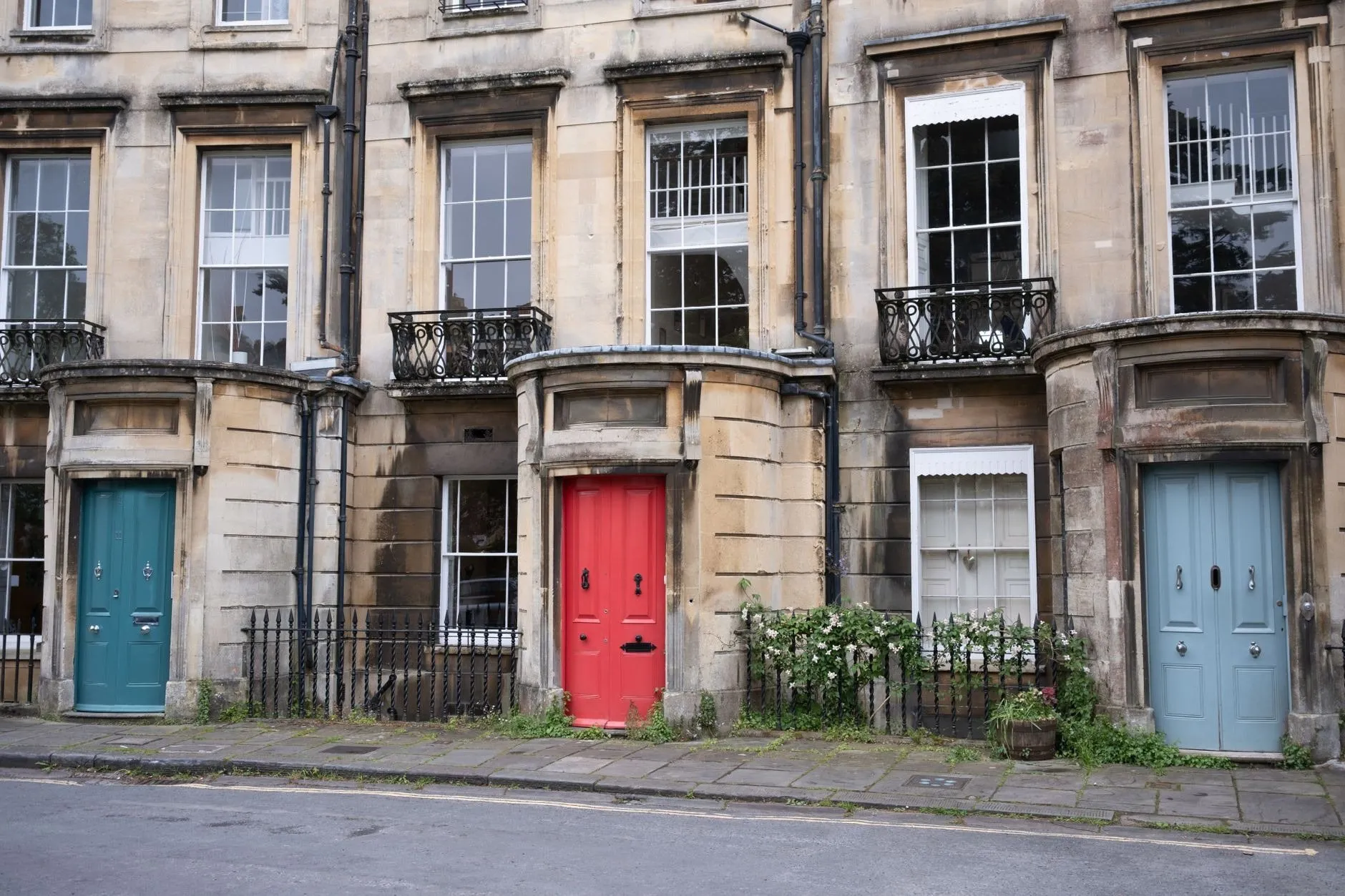 Georgian terraced houses in Bath stone with teal, red and pale blue front doors
