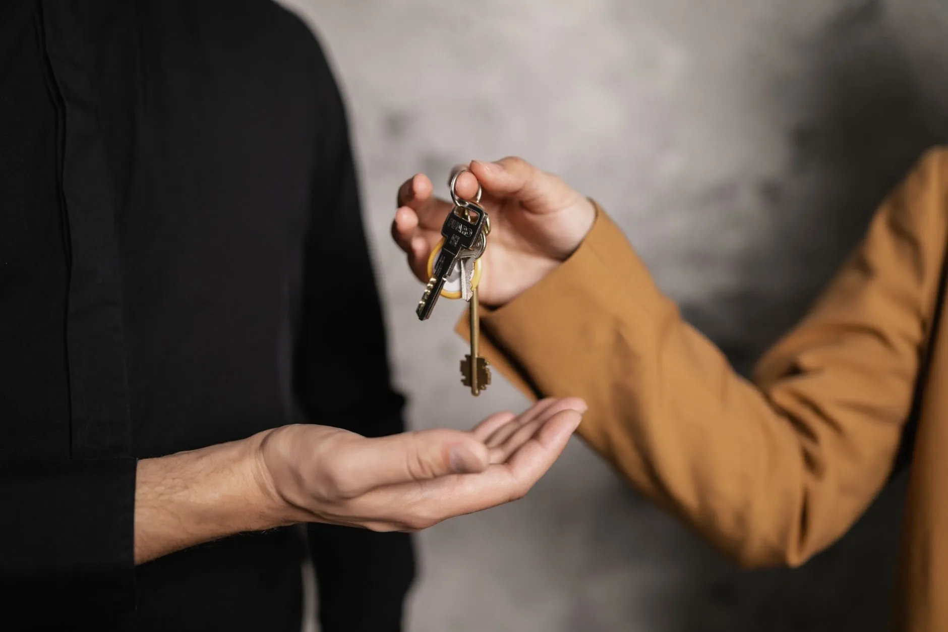 One person handing a bunch of house keys into another's open palm